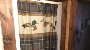 Cortina de ducha con estampado de cuadros y diseños de patos.