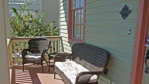 Une véranda aménagée avec des meubles en osier, notamment un canapé et deux fauteuils, ainsi qu’une petite table.