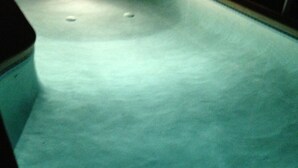 A swimming pool with a curved edge and a light source at the far end.