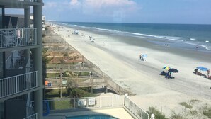 Een zwembad met ligbedden, uitzicht op het strand en een redderpost.