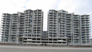 Een modern hoog woongebouw met meerdere balkons en een centrale binnenplaats.