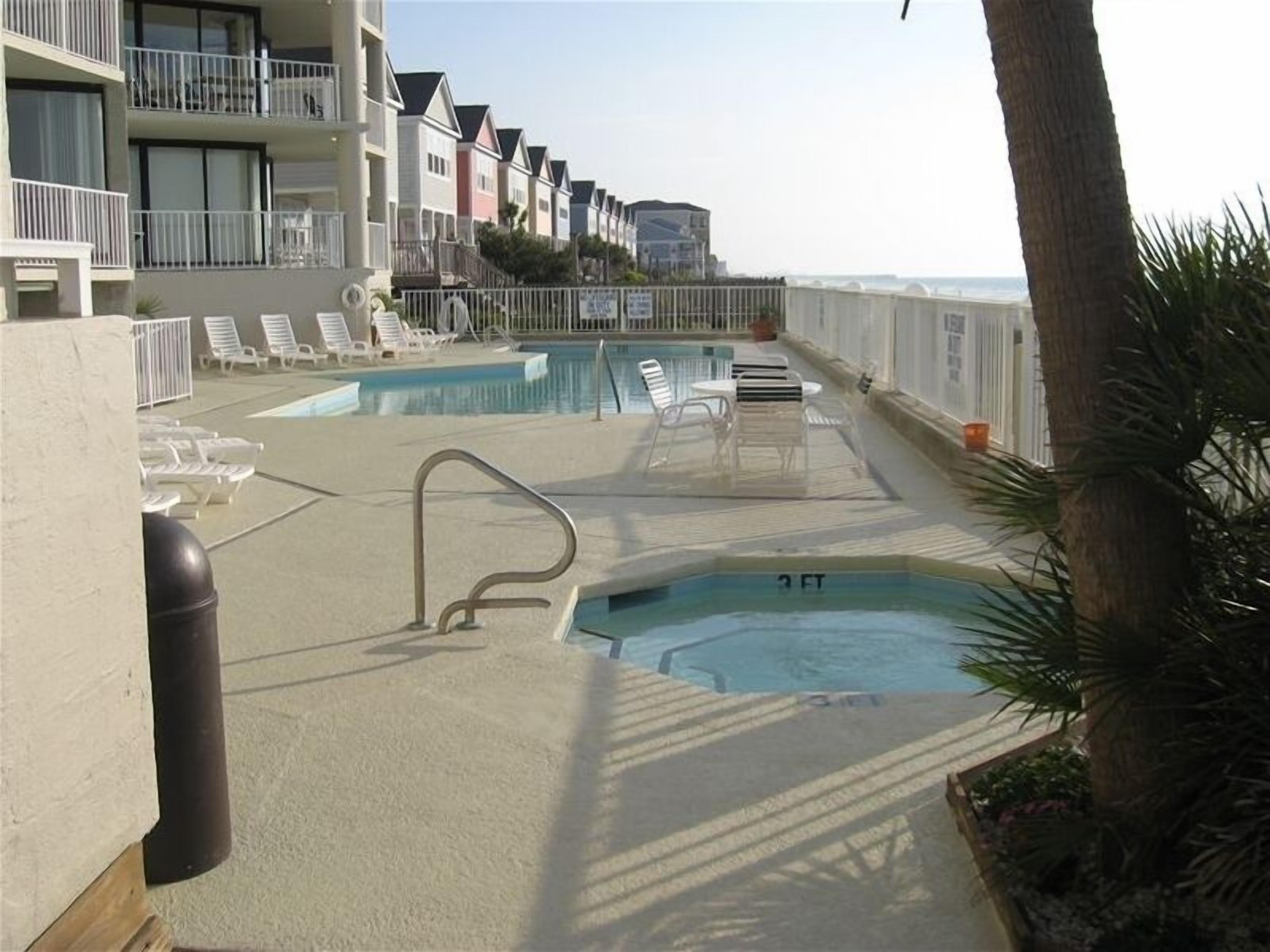 Un área de piscina con sillones de descanso y un jacuzzi pequeño.