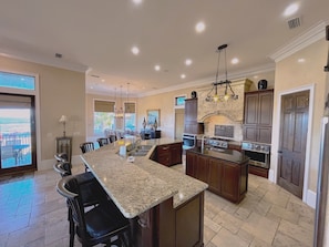 A spacious kitchen with granite countertops, dark wooden cabinets, and a central island.