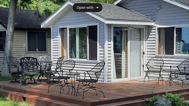 Ein kleines Haus mit einer Terrasse, ausgestattet mit Sitzgelegenheiten und einer Glastür.