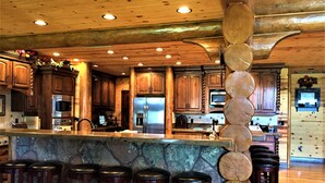 Une cuisine spacieuse avec des meubles en bois, un îlot central doté de tabourets et des appareils électroménagers modernes.