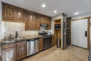 A kitchen with wooden cabinets, stainless steel appliances, a granite countertop, and a tiled floor. - Freshly Remodeled One Bedroom Near Canyon Village at Park City Mountain Resort (Park City)