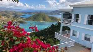 A two-story building with a balcony overlooking a pool and a scenic view of a bay with boats.