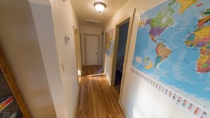 Un pasillo con piso de madera, un gran mapa mundial en la pared derecha y una puerta al final.