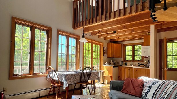 A spacious living area with a dining table, a sofa, and a kitchen in the background. - Beautiful Vacation Cottage with a View in Newfane, Vermont, near Mt. Snow (Newfane)