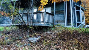 A rustic cabin with a wooden deck and a porch, surrounded by autumn foliage. - Beautiful Vacation Cottage with a View in Newfane, Vermont, near Mt. Snow (Newfane)