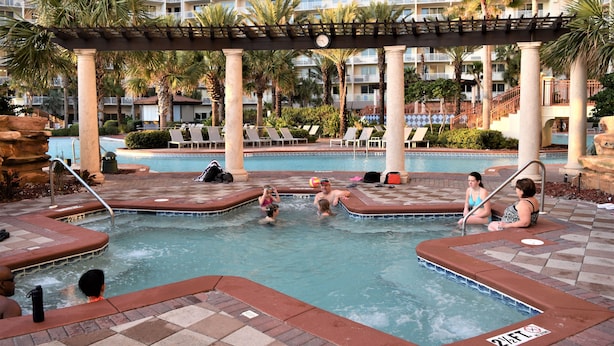 A pool area with lounge chairs, palm trees, and a hotel building in the background. - Beach Front/Free Beach Chair Service & Wifi/ Reserved Parking/ Best Amenities (Panama City)