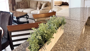 A modern living room with a sofa, a dining table with chairs, and a kitchen area with granite countertops and a sink. - Beach Front/Free Beach Chair Service & Wifi/ Reserved Parking/ Best Amenities (Panama City)
