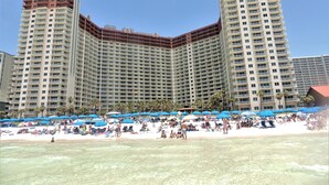 A high-rise hotel with multiple balconies, a beach in front, and numerous umbrellas. - Beach Front/Free Beach Chair Service & Wifi/ Reserved Parking/ Best Amenities (Panama City)