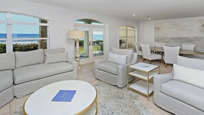 A modern living room with a round coffee table, white sofas, and armchairs. There are large windows with a view of the ocean. - Gorgeous Overlooking Gulf,Patio, Pool, Grill (Santa Rosa Beach)