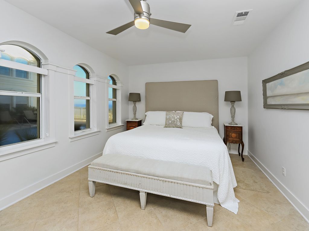 A bedroom with a large bed, a ceiling fan, and two bedside tables with lamps.