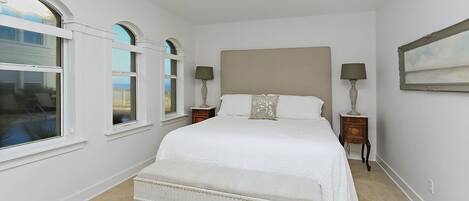A bedroom with a large bed, a ceiling fan, and two bedside tables with lamps.