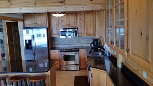 A kitchen with wooden cabinets, a stainless steel refrigerator, a microwave, an oven, and a sink. - Beautiful Burt Lake sunsets and sandy beach (Indian River)