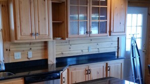 A kitchen with wooden cabinets, a black countertop, and a window. - Beautiful Burt Lake sunsets and sandy beach (Indian River)