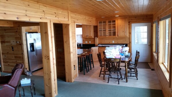 A wooden interior with a kitchen area, dining table, and chairs.