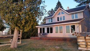 A two-story house with a deck and a large windowed porch. - Beautiful Burt Lake sunsets and sandy beach (Indian River)