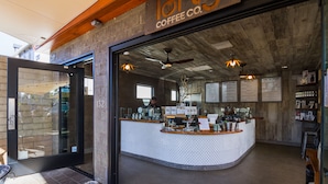 Uma cafeteria com interior rústico, balcão com menu e teto de madeira.