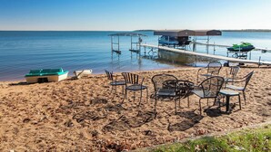 Een strand met een pier, stoelen en een boot.