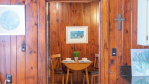 Une pièce aux murs lambrissés, avec une table ronde, deux chaises, un tableau encadré accroché au mur et une petite plante posée sur la table.