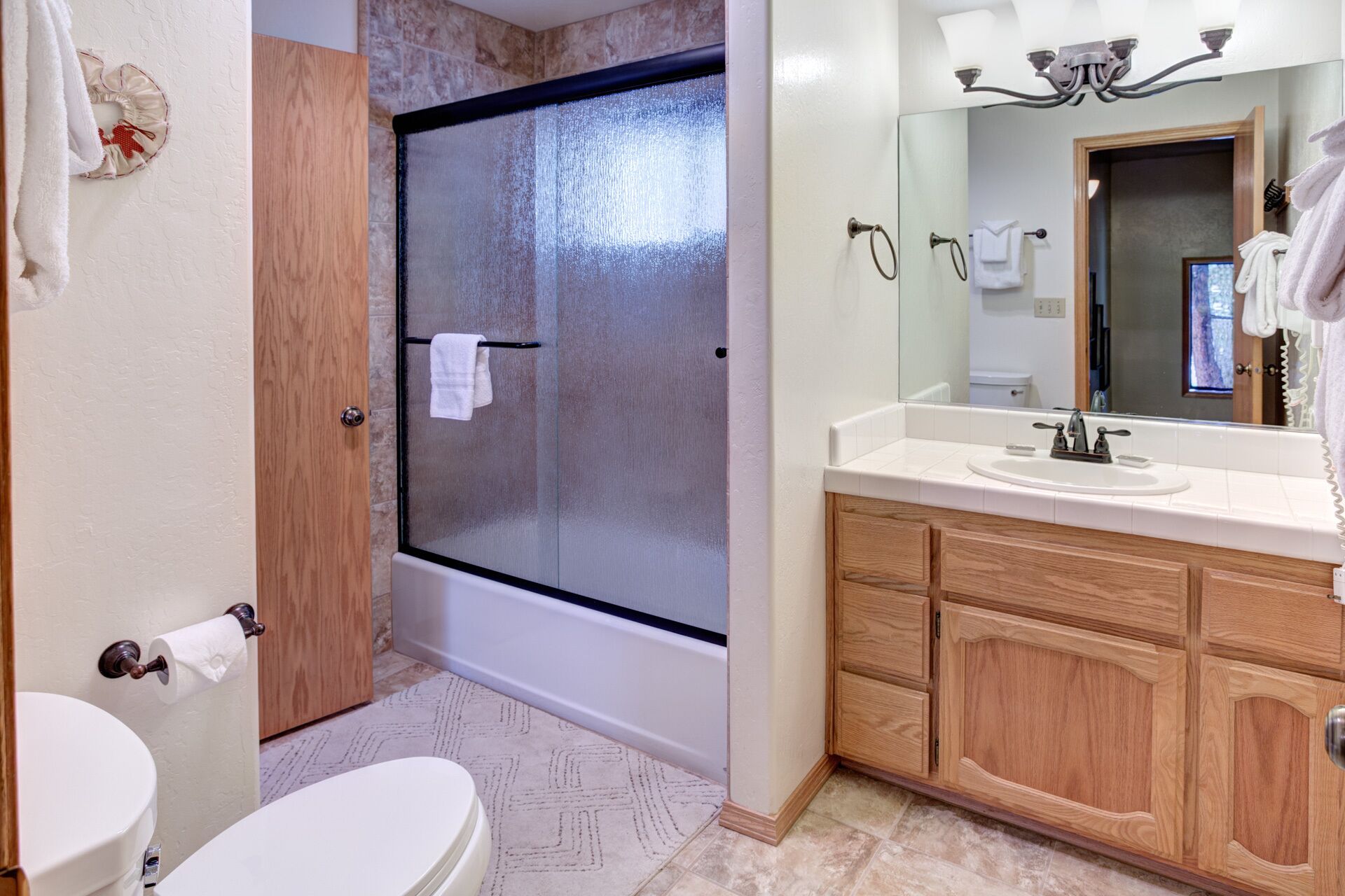 A bathroom with a shower, toilet, and vanity with a mirror.