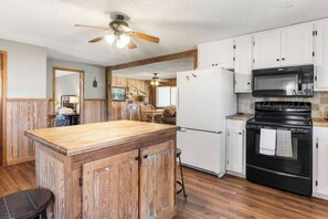 A kitchen with a wooden island, white cabinets, a black stove, and a microwave.