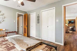 A bedroom with a bed, a bench, a wardrobe, and a door leading to another room.
