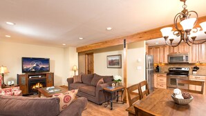 Una sala de estar acogedora con chimenea, televisor y comedor con muebles de madera.