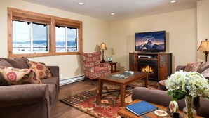 Una sala de estar acogedora con chimenea, asientos cómodos, televisión y vistas al exterior.