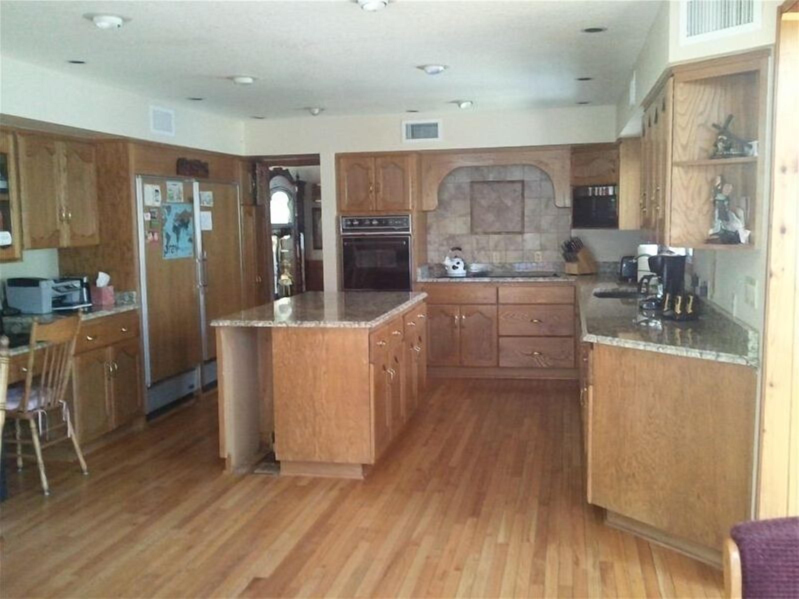 A kitchen with wooden cabinets, a granite countertop, and a built-in oven.
