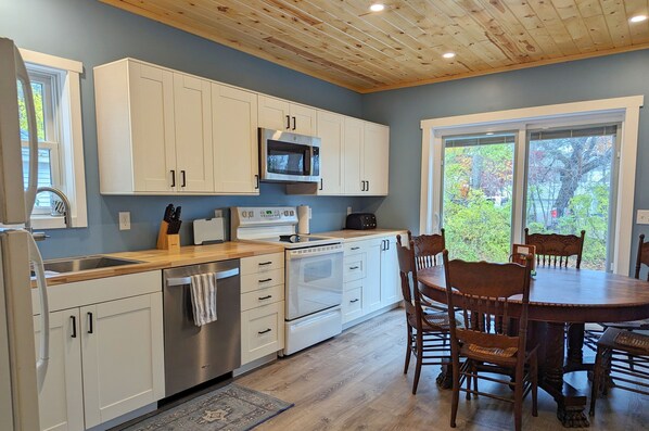 A modern kitchen with white cabinets, stainless steel appliances, and a wooden dining table with chairs.