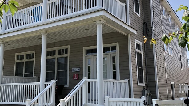 A two-story house with a porch, white railings, and a number '932' on the front door.