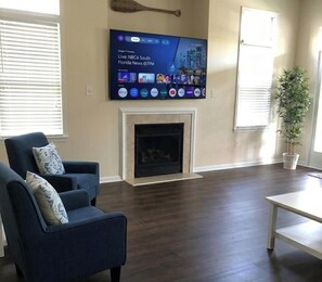 A living room with a flat-screen TV mounted on the wall, a fireplace, and a potted plant. - Booking 2027. 4 Level Townhome, Rare Find! (Ocean City)
