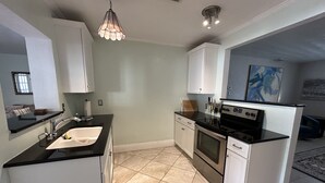 Una cocina moderna con armarios blancos, encimera negra y estufa de acero inoxidable.