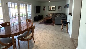 Un salón amplio con comedor, un sofá gris y un televisor.