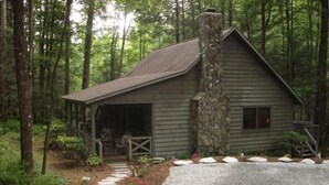 A rustic cabin with a stone chimney, surrounded by a forest. - 3BR/2BA. Mtn Cabin- Cool, Rocky Mtn. Stream. Prime Fall weeks available (Cashiers)