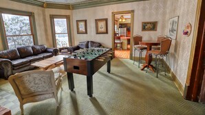 A cozy living room with a foosball table, a leather sofa, and a dining area with chairs.