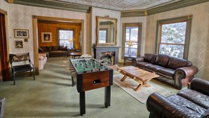 A cozy living room with a foosball table, leather sofas, a fireplace, and a large mirror.