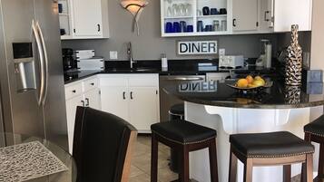 A modern kitchen with a built-in island, bar stools, and a 'DINER' sign.
