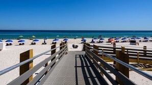 A beach with a wooden walkway leading to the shore, featuring sun loungers and umbrellas. - LAVISH OCEAN OASIS! DIRECTLY on the GULF, POWDERED SAND - ABUNDANT AMENITIES! (Orange Beach)