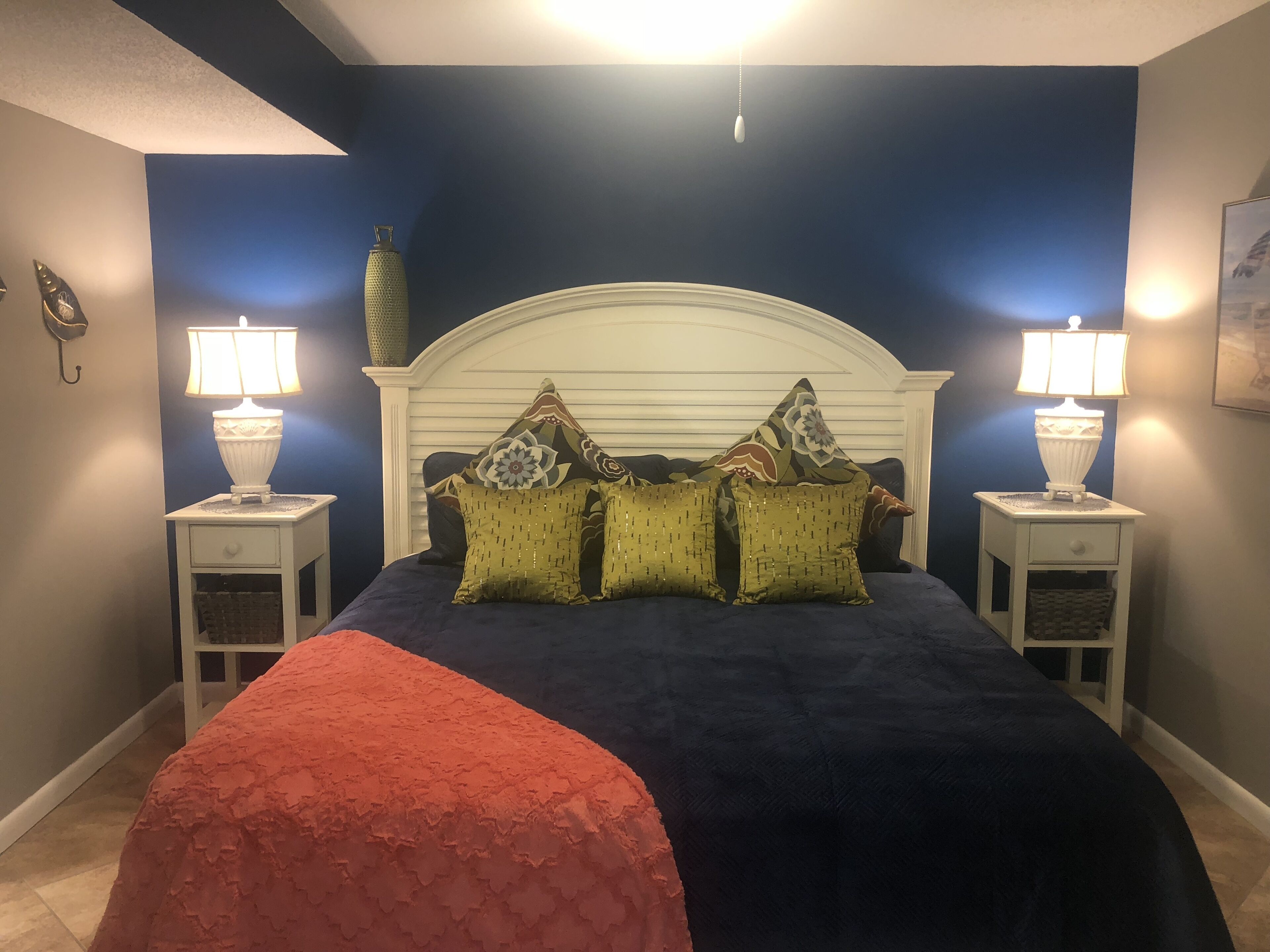 A bedroom with a bed, two nightstands with lamps, and a decorative vase on the nightstand.