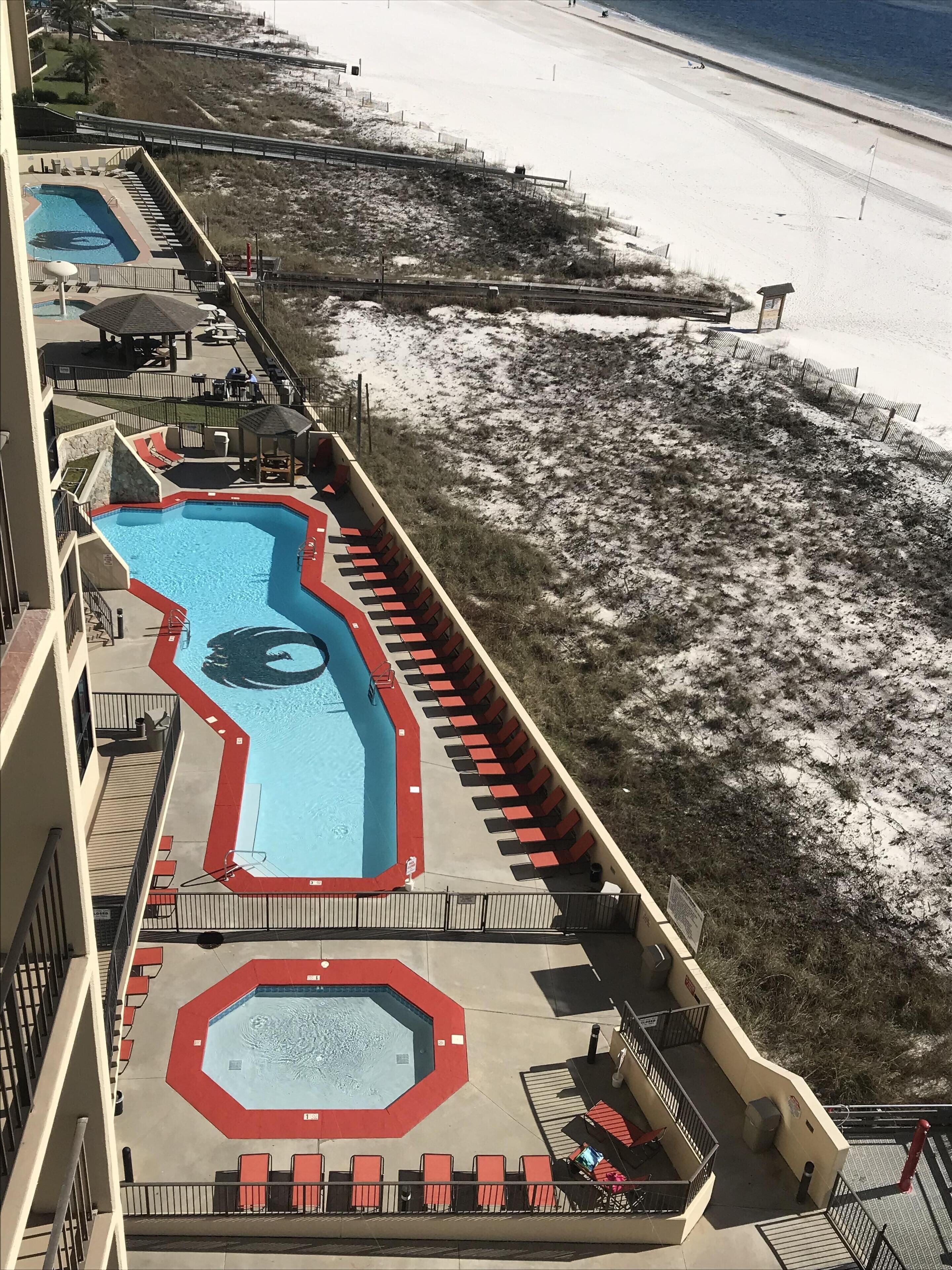 Un espace piscine doté d’un aménagement original, comprenant une grande piscine et une plus petite piscine octogonale, le tout entouré de chaises longues rouges et noires.