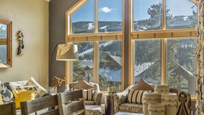 Ein gemütliches Wohnzimmer mit einem großen Fenster, das einen Blick auf eine verschneite Berglandschaft bietet.