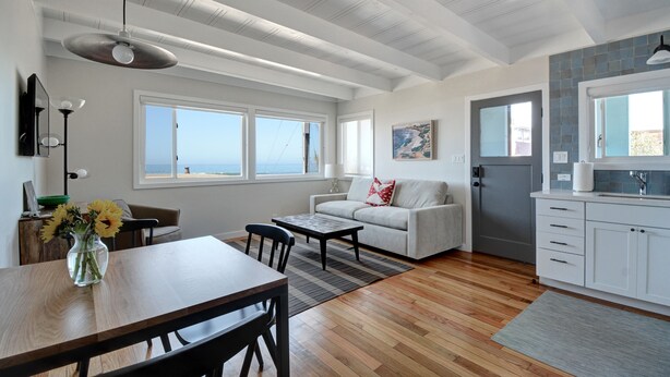 A spacious living area with a dining table, sofa, and kitchen.