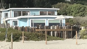 A two-story beach house with a wooden fence and a covered patio.