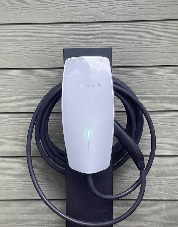 A Tesla electric vehicle charging station with a cable connected to it.