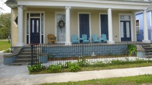 A two-story house with a porch, a front door, and a small front yard with a fence.